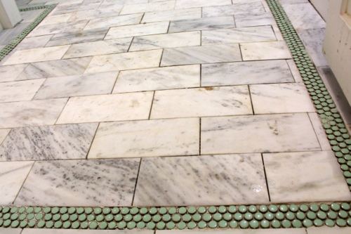 Green, penny tile accent among the sea of marble.